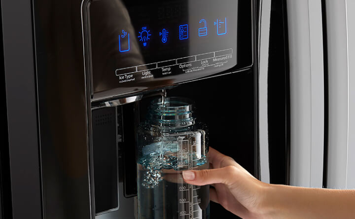 Close-up image of a water bottle being filled with water from a refrigerator dispenser. Close-up image of a water bottle being filled with water from a refrigerator dispenser.