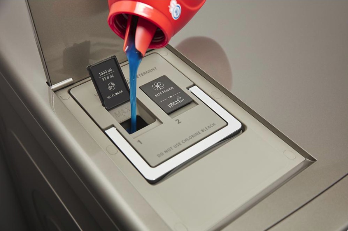 A person pours detergent into the detergent dispenser of a washing machine.