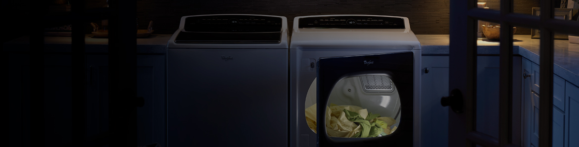 A washer and dryer set in a large, dark laundry room.
