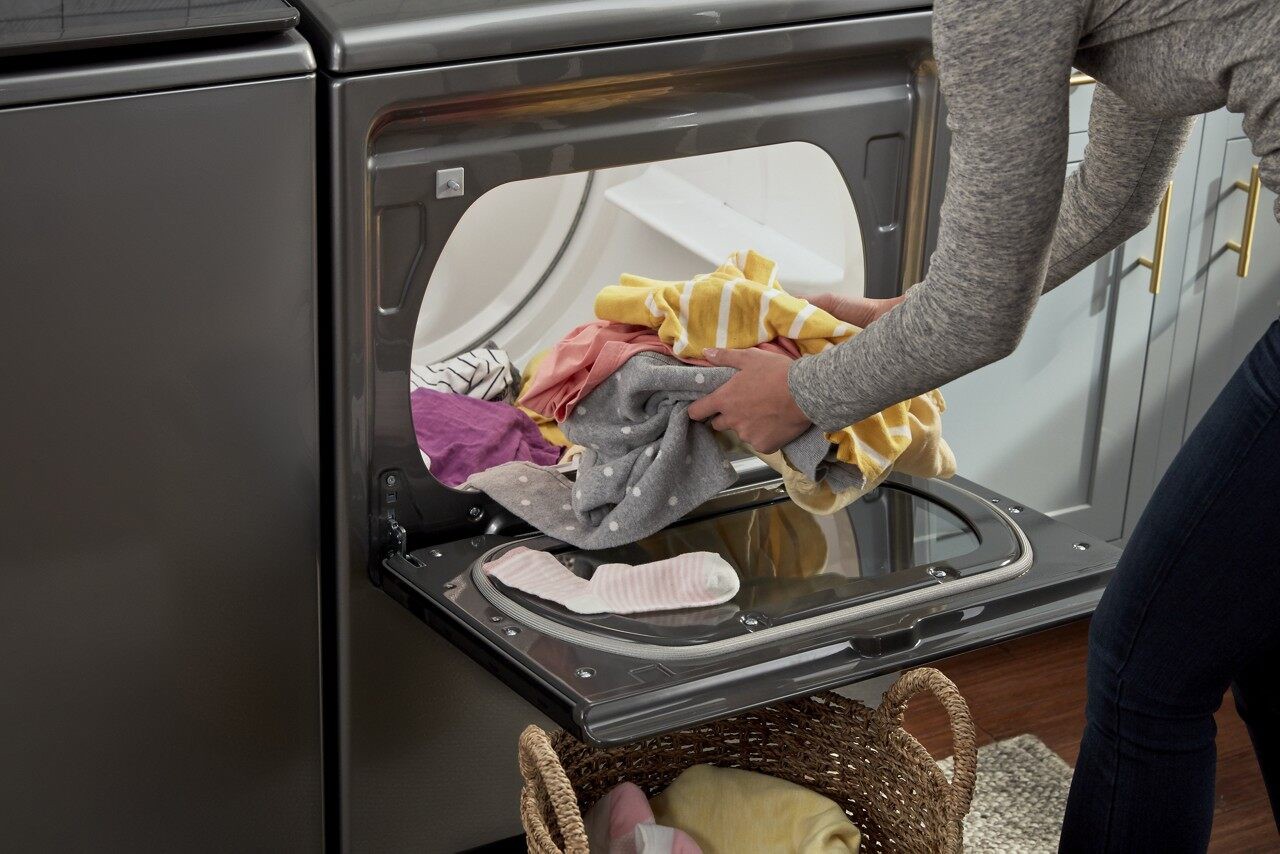 A person getting clothes out of a dryer.