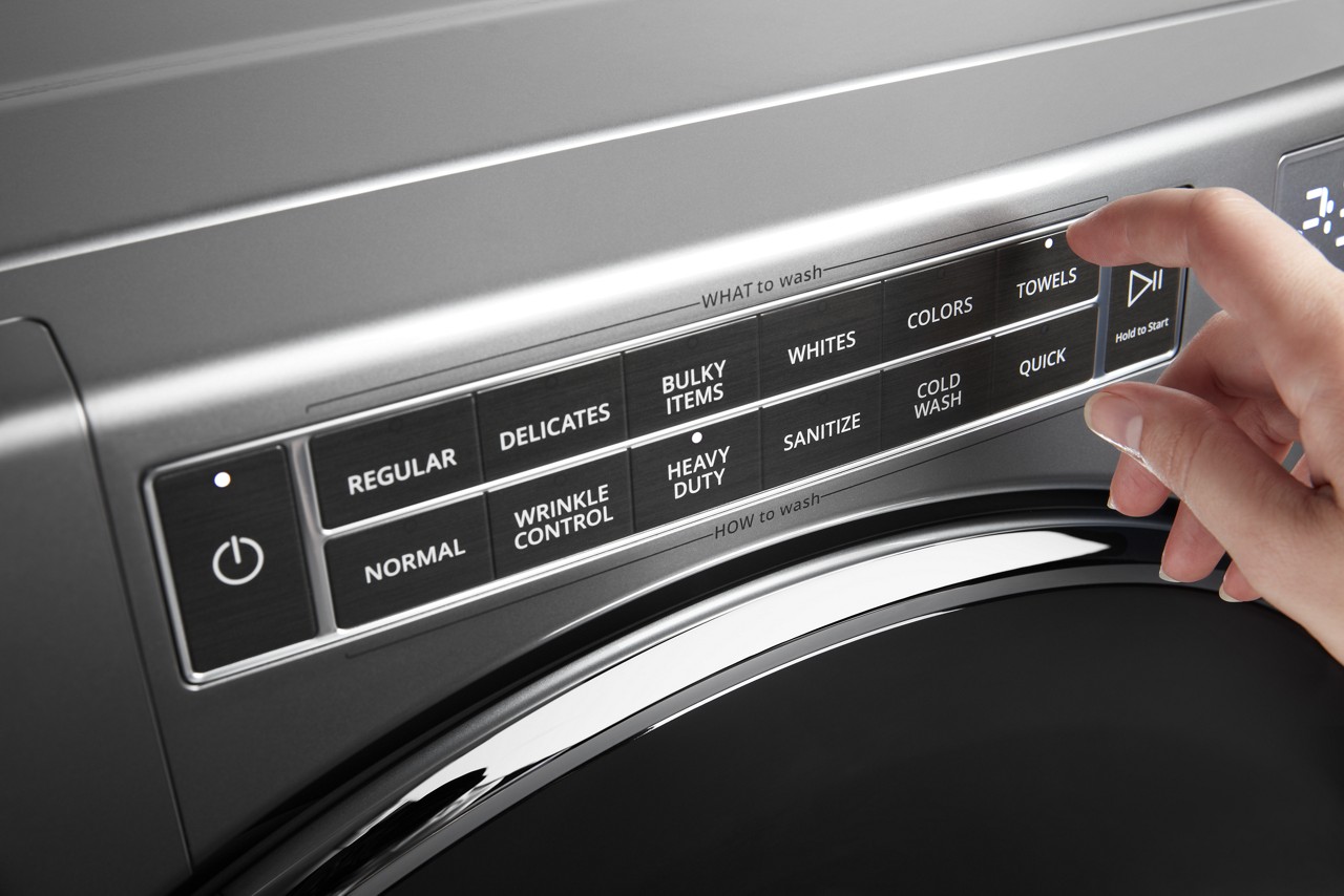 A person selects a cycle from a washing machine control panel. A person selects a cycle from a washing machine control panel.