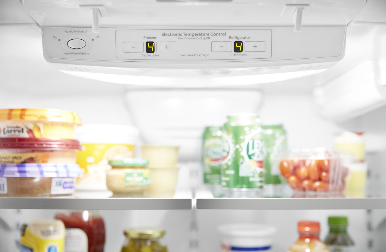 Un thermomètre de réfrigérateur avec des aliments en arrière plan.