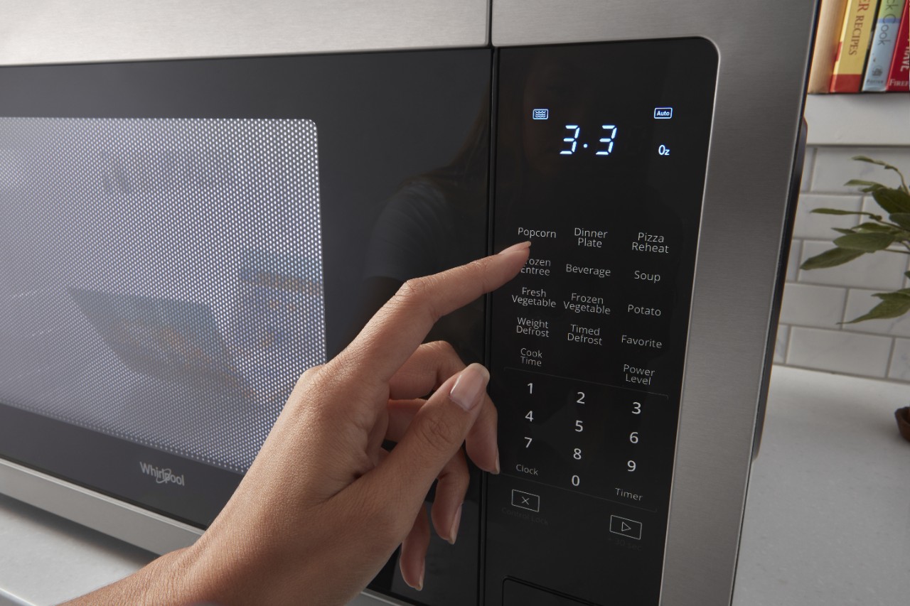 personne appuyant sur le bouton d'un four à micro-ondes