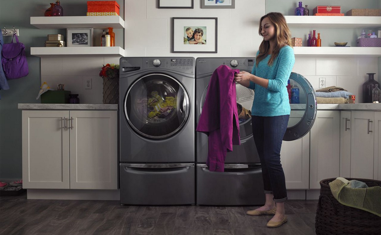Woman removing sweater from front loading dryer Woman removing sweater from front loading dryer