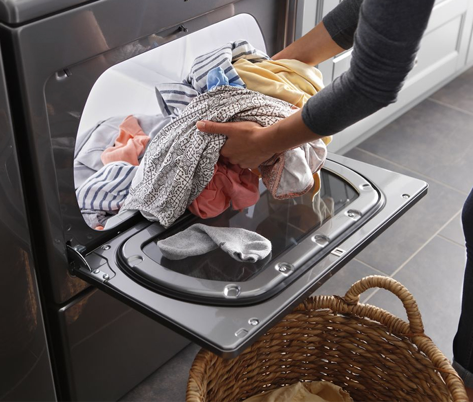 Person loading dryer with clothes Person loading dryer with clothes