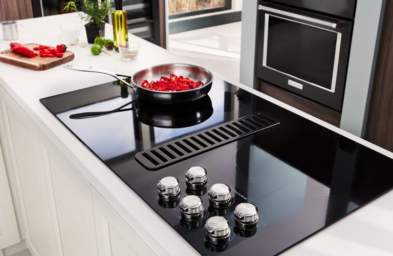 Downdraft Electric Cooktop With Frying Pan and Vegetables in Modern Kitchen