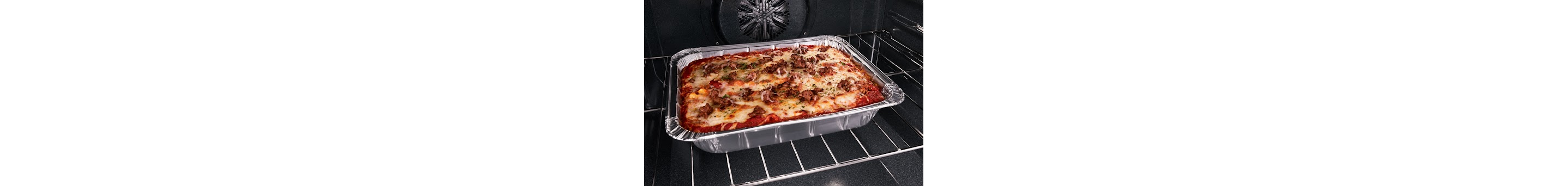 Un plat de pâtes gratinées avec des morceaux de viande sur le dessus. Le plat est aluminum se trouve sur la grille d’un four Whirlpool.
