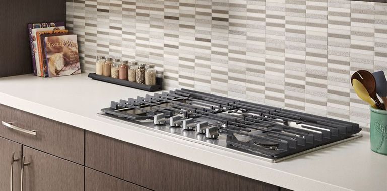 Whirlpool Gas Cooktop Installed On White Marble With Grey and White Backsplash
