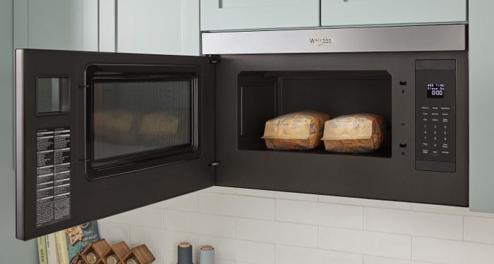 An opened Whirlpool Over-the-Range Microwave with two bags of popped popcorn
