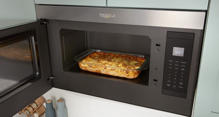 A Whirlpool Over-the-Range Microwave with its door opened. Inside is a casserole dish