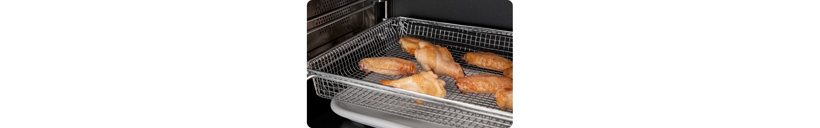 L'intérieur d'un four Whirlpool dans lequel des ailes de poulet cuisent dans un panier à friture à air