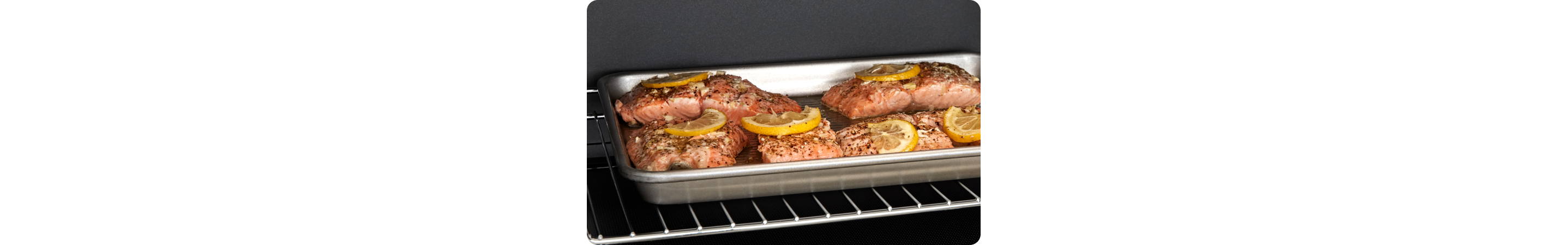 L'intérieur d'un four Whirlpool dans lequel se trouve une plaque de cuisson contenant des filets de saumon garnis de tranches de citron en train de cuire