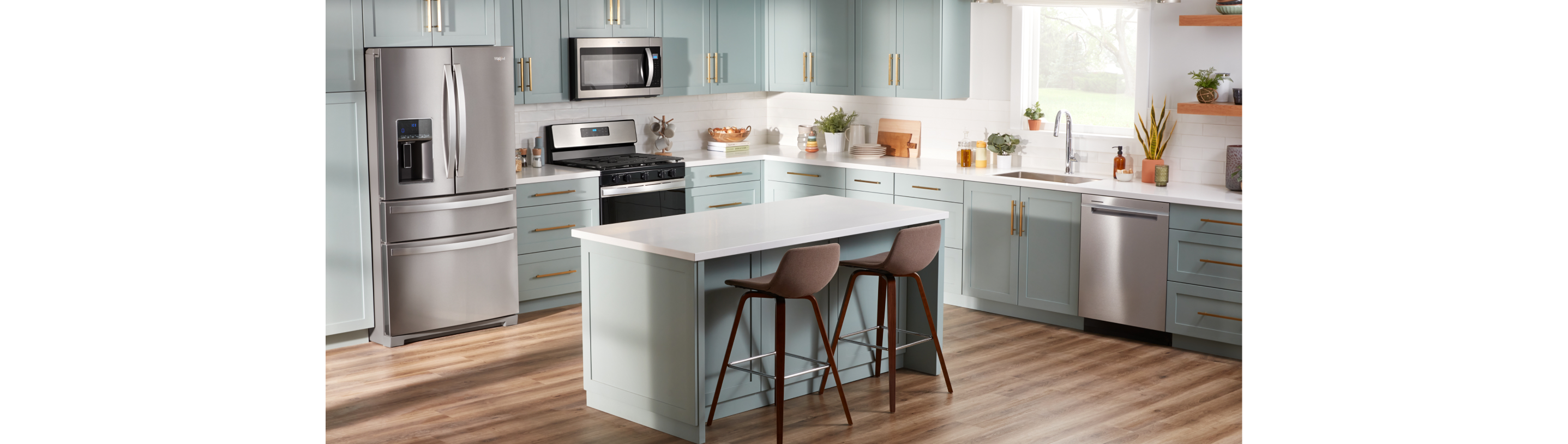 A kitchen with a Whirlpool French Door Refrigerator, a Whirlpool Oven with an Over-the-Range Microwave and a Whirlpool Dishwasher. There's an island with two chairs and on the counters are potted plants, cutting boards, mugs hanging on a stand and other items