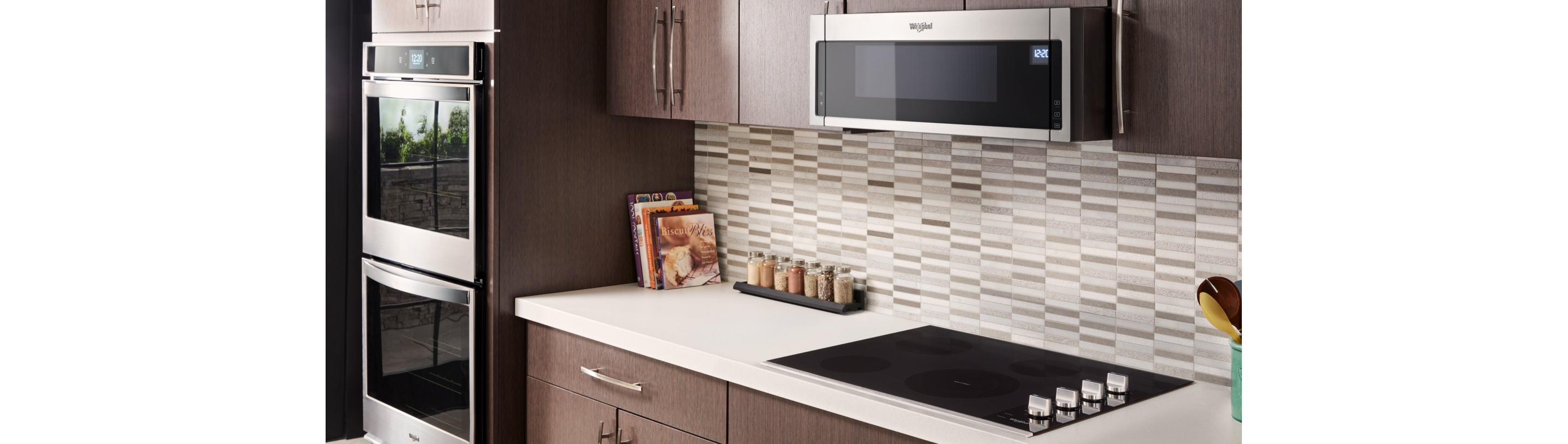 A kitchen with a Whirlpool Cooktop, a Whirlpool Over-the-Range Microwave and a Whirlpool Double Wall Oven. On the counters are cookbooks and a tray of spices