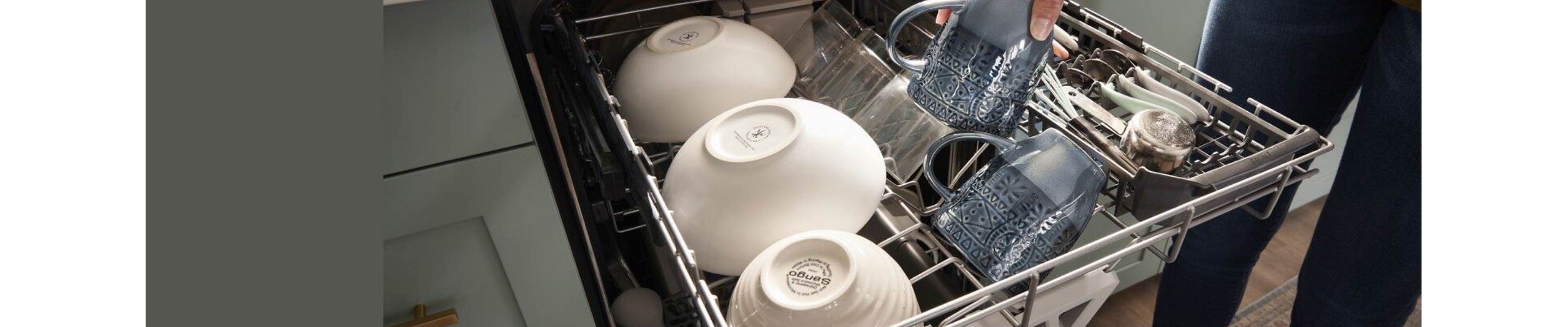 The top rack of a dishwasher pulled out. On the rack is a row of white bowls, a row of glasses. where a hand is removing a glass, and cutlery in a cutlery tray.