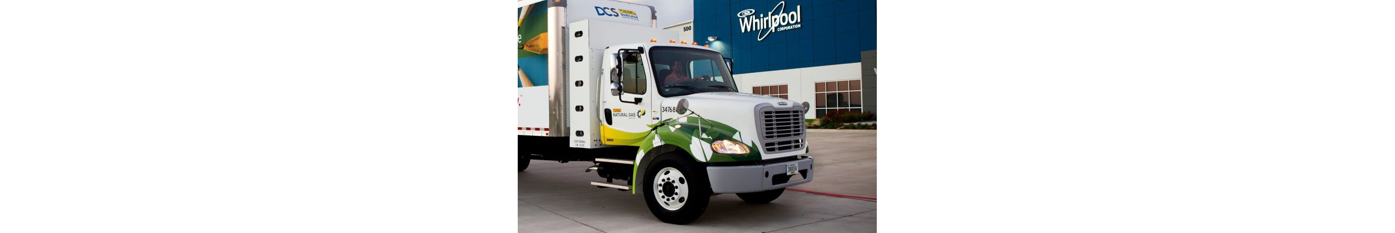 A Whirlpool delivery truck in the yard of a Whirlpool building.