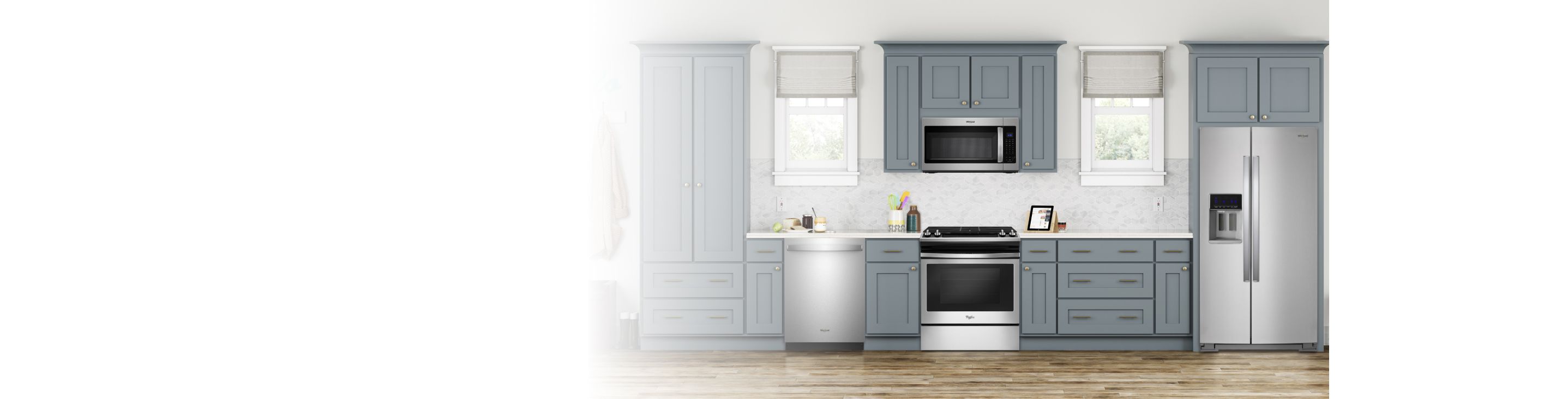 A kitchen with grey cabinets and two windows. There are several appliances, including a Whirlpool Range, Whirlpool Over-the-Range Microwave, Whirlpool Dishwasher and Whirlpool Refrigerator