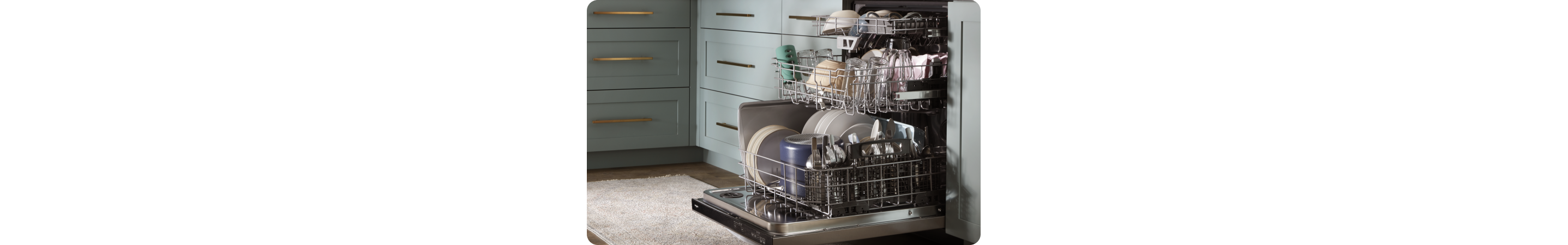 In a kitchen with grey cabinets is a dishwasher. It's opened and the racks are pulled out. Each rack is full of items like dishes, bowls, cups and more