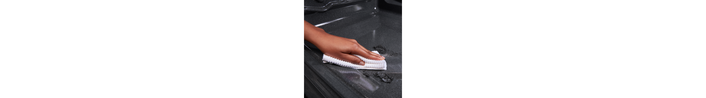 Person cleaning an oven with a white cloth